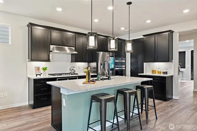 a kitchen with stainless steel appliances kitchen island a refrigerator and a stove top oven