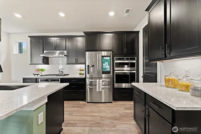 a kitchen with stainless steel appliances granite countertop a refrigerator a stove and a sink
