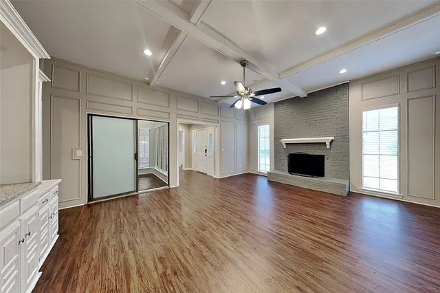 an empty room with wooden floor fireplace and windows