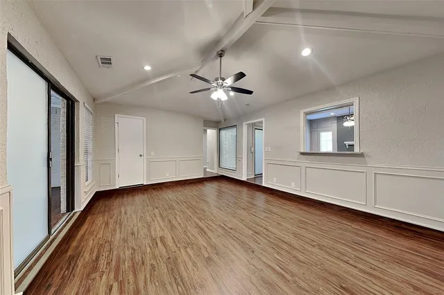 a view of an empty room with a window and wooden floor