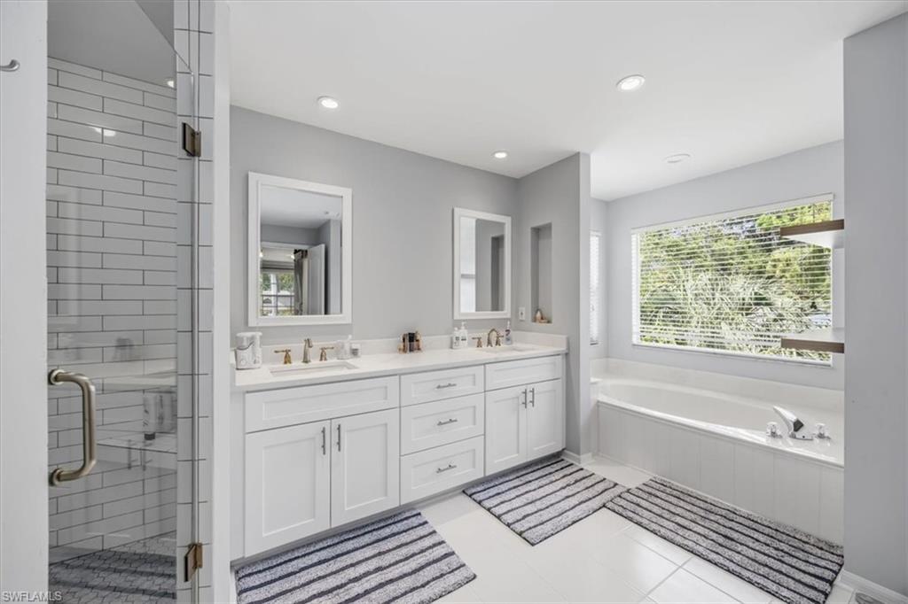 2066 Imperial Circle Naples, FL 34110 - Photo 17 of 29 a spacious bathroom with a double vanity sink a large mirror and a bathtub