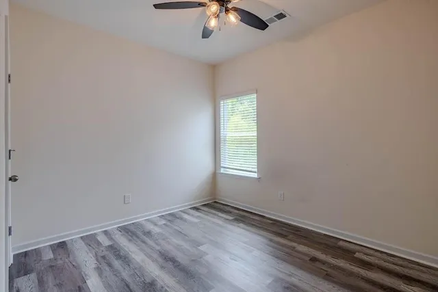 an empty room with a window and a ceiling fan