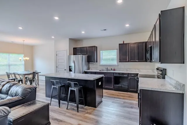 a large kitchen with stainless steel appliances granite countertop a table chairs sink refrigerator and cabinets