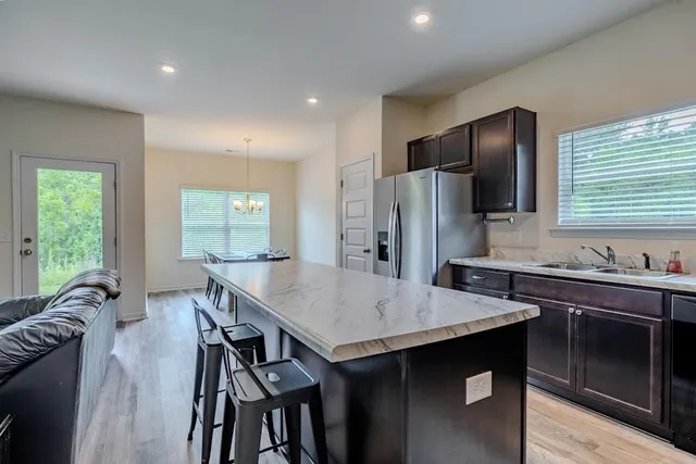 a kitchen with granite countertop a table chairs stainless steel appliances and window