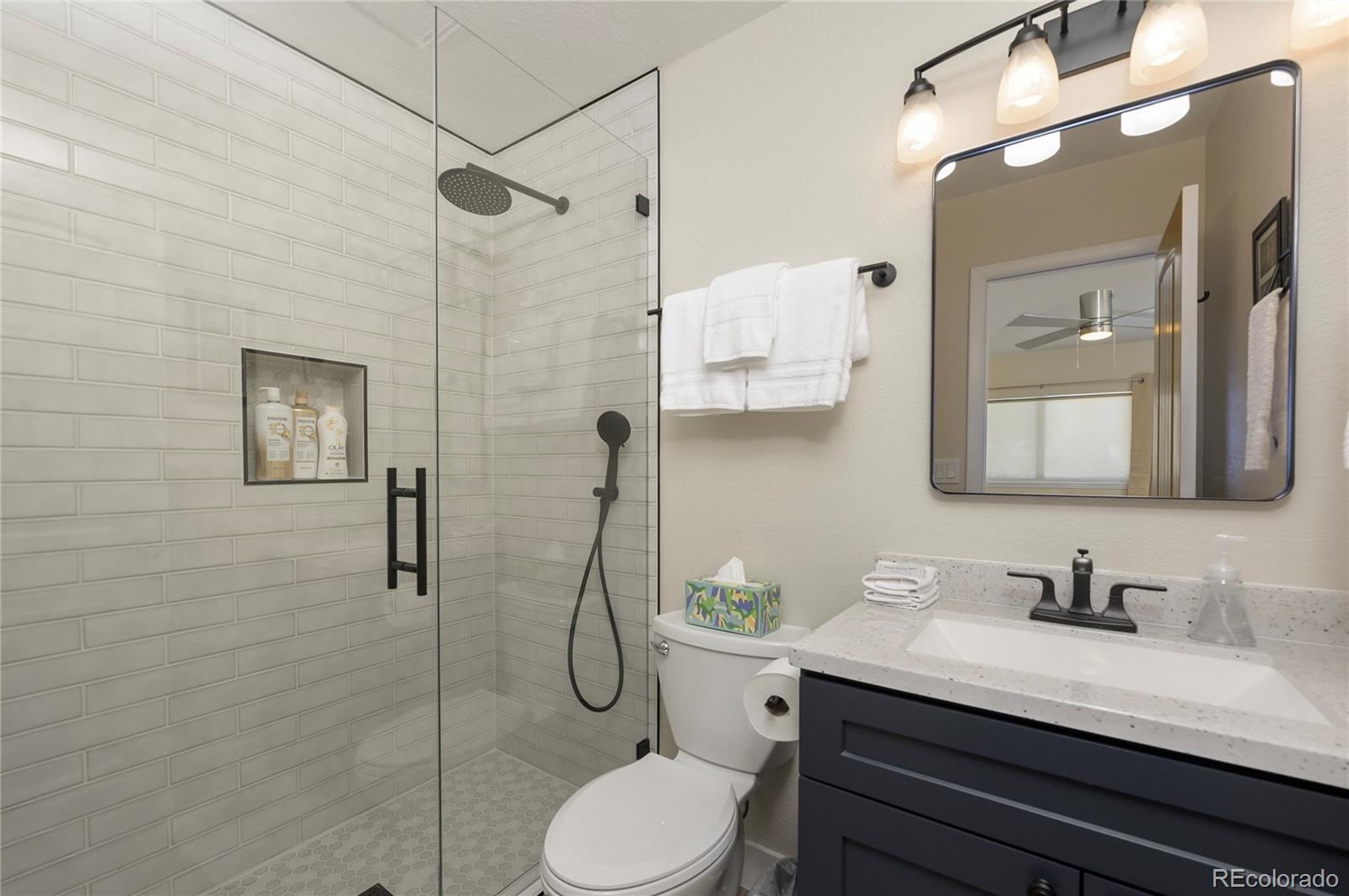 83 County Road, Unit F7 Fraser, CO 80442 - Photo 12 of 20 a bathroom with a granite countertop sink toilet a mirror and shower