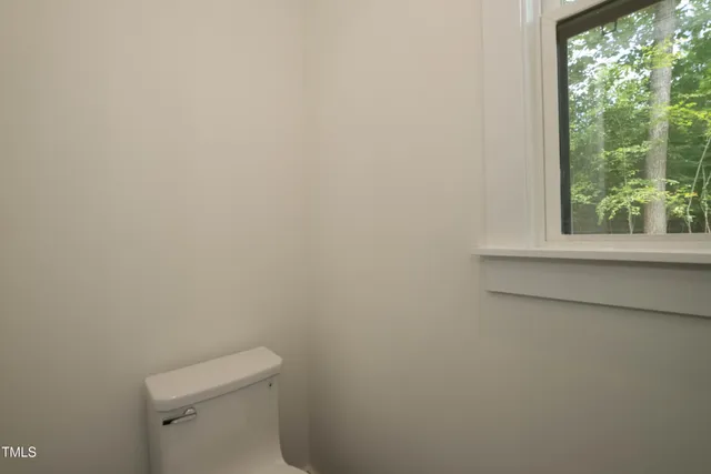 a white toilet sitting in a bathroom next to a window