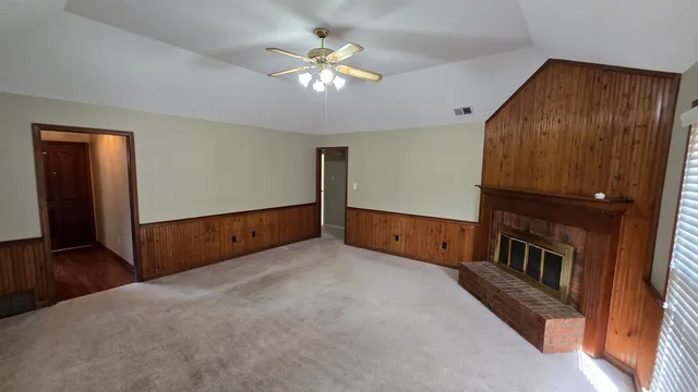a view of an empty room with chandelier fan and a window