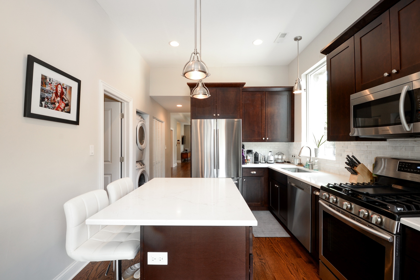1545 North Claremont Avenue, Unit 2 Chicago, IL 60622 - Photo 3 of 13 a large kitchen with stainless steel appliances a stove a sink dishwasher a dining table and chairs with wooden floor