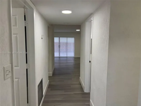 a view of a hallway with wooden floor and closet