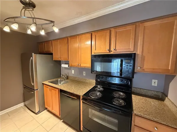 a kitchen with granite countertop a stove top oven microwave and refrigerator