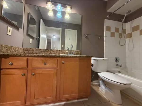 a bathroom with a granite countertop sink mirror vanity and toilet