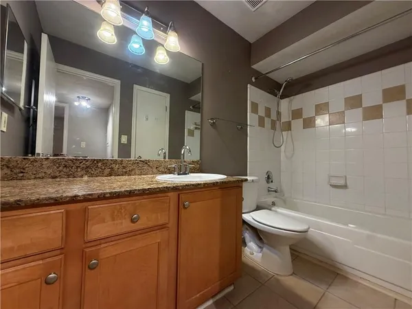 a bathroom with a granite countertop sink toilet mirror and bathtub