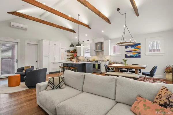 a living room with furniture kitchen view and a wooden floor