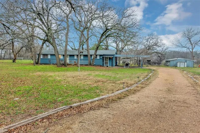a view of a house with a big yard and large trees