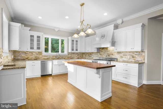 a kitchen with kitchen island granite countertop a sink cabinets and wooden floor