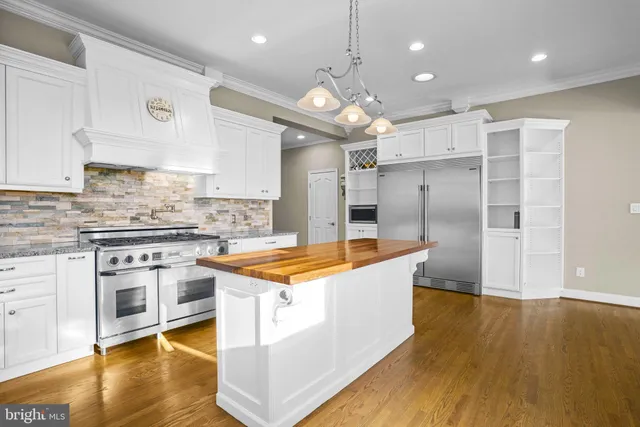 a large kitchen with stainless steel appliances granite countertop a sink a stove and a refrigerator