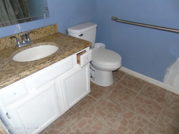 a bathroom with a granite countertop sink and a toilet
