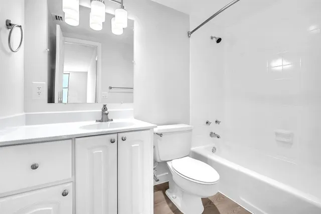 a bathroom with a sink a toilet a mirror a vanity and bathtub