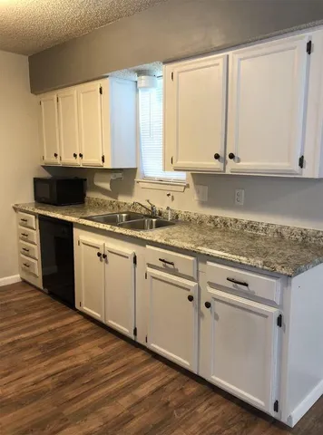 a kitchen with granite countertop white cabinets and a sink