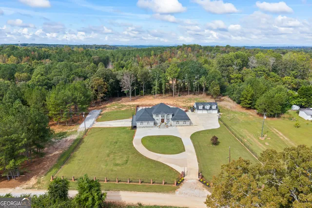 an aerial view of a house with swimming pool and large trees