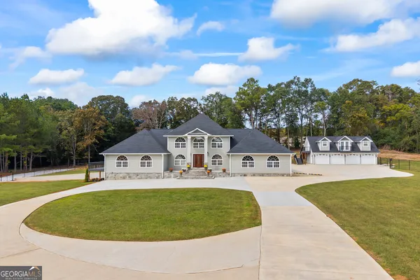 an aerial view of a house with swimming pool and large trees