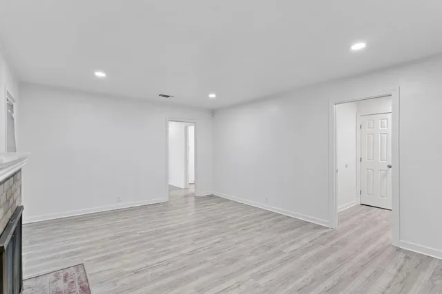 a view of an empty room with wooden floor and a fireplace