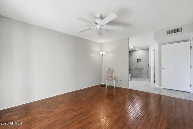 a view of an empty room with a window and wooden floor