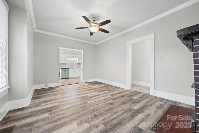 a view of an empty room with wooden floor fireplace and a window