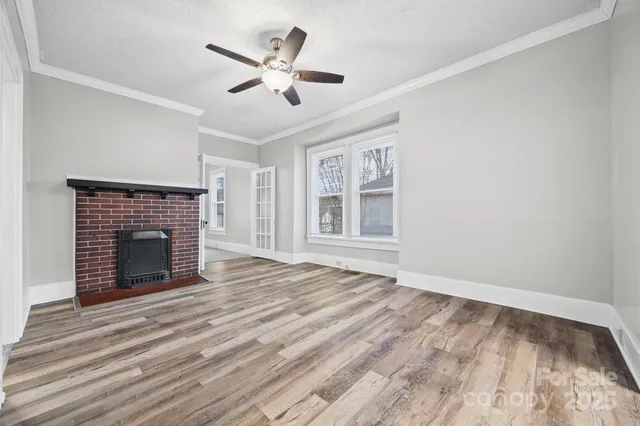 a view of an empty room with a window and a kitchen