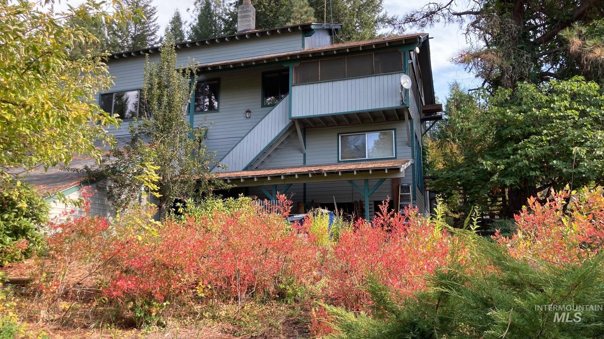 266 Falcon Ridge Road Kooskia, ID 83539 - Photo 3 of 50 Two-story exterior featuring light blue siding, multiple windows, and a screened upper balcony as well as additional view of the garden