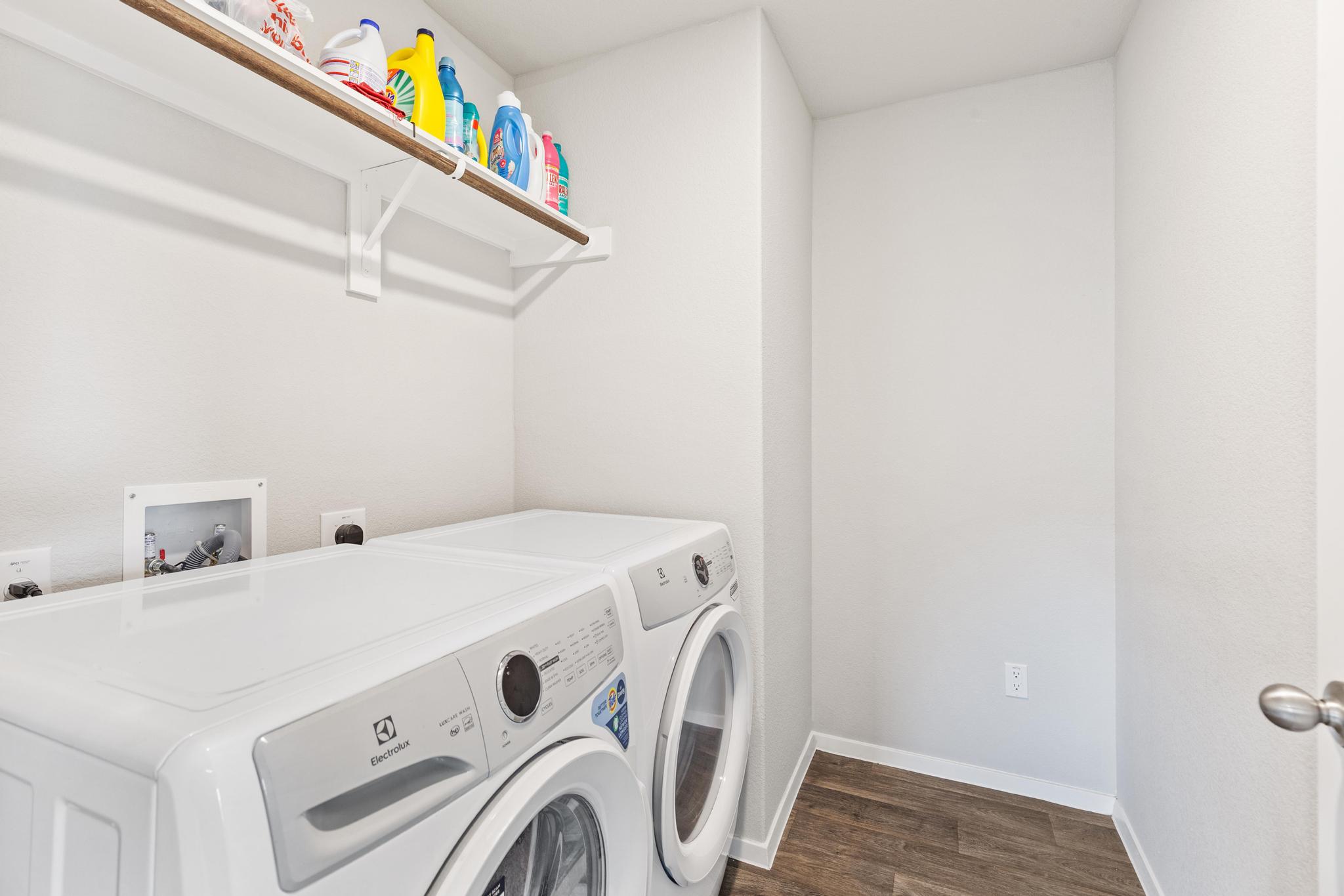 242 Barley Lane Elgin, TX 78621 - Photo 23 of 31 Dedicated laundry area featuring wood-finish flooring, white walls, and a built-in shelving unit