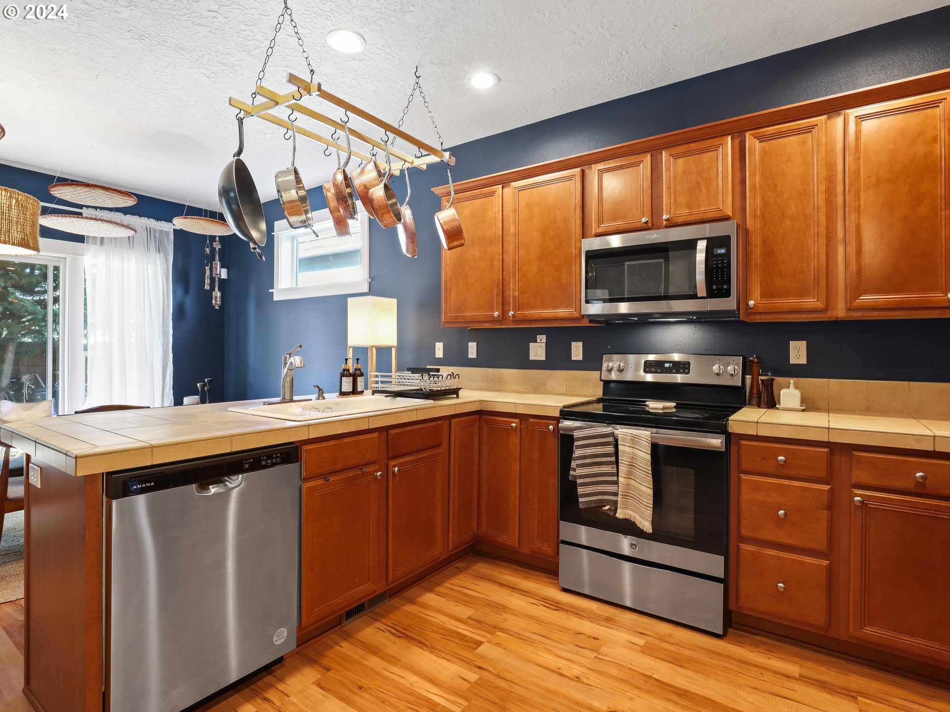 6924 Southeast Boise Street Portland, OR 97206 - Photo 8 of 45 a kitchen with stainless steel appliances granite countertop a stove sink microwave and window
