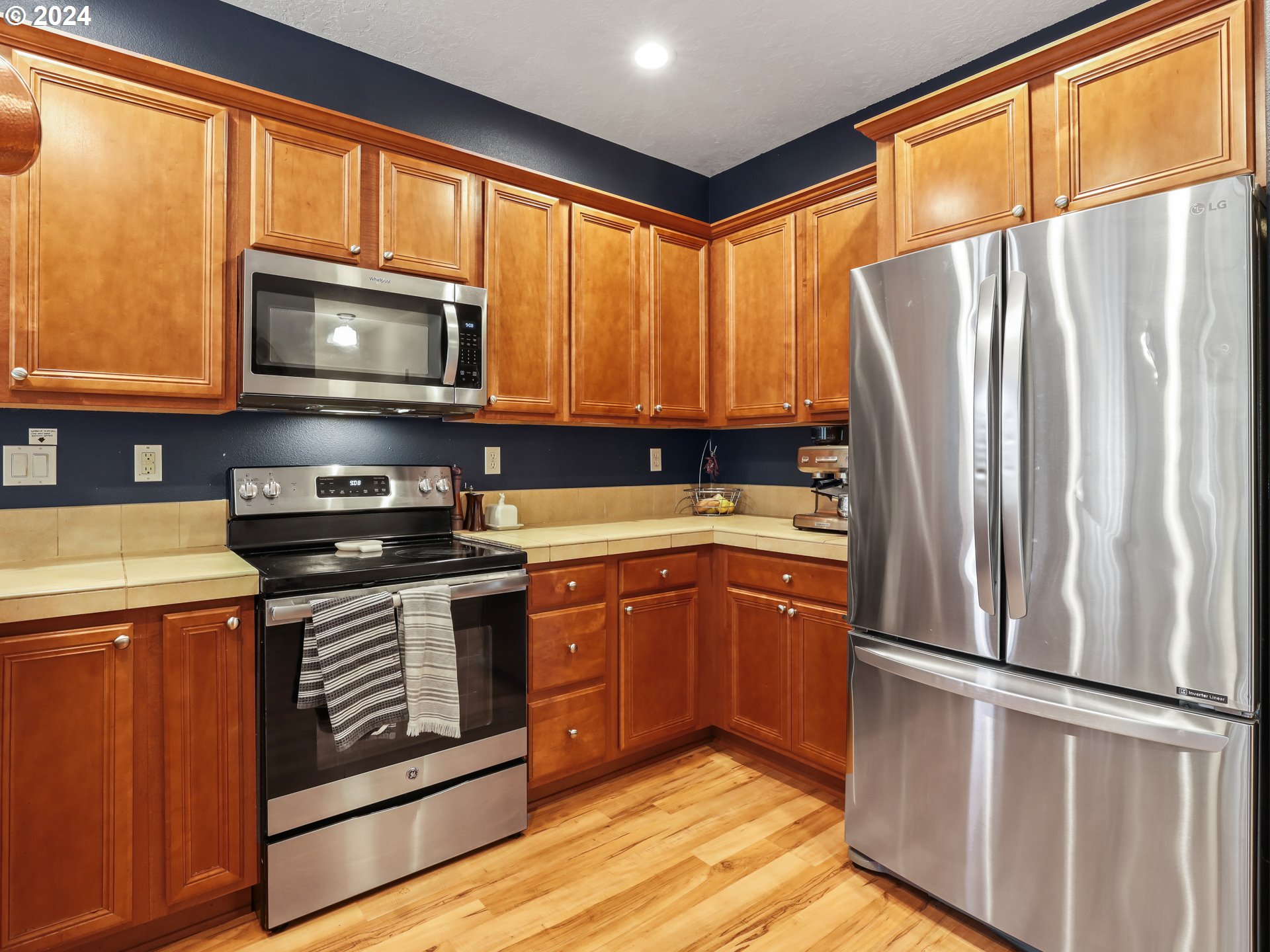 6924 Southeast Boise Street Portland, OR 97206 - Photo 9 of 45 a kitchen with stainless steel appliances granite countertop a refrigerator oven a sink dishwasher and wooden cabinets with wooden floor