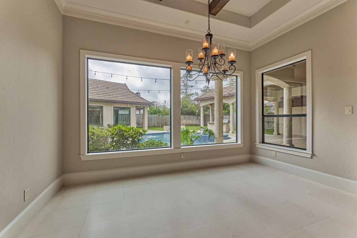 25 Post Shadow Estate Drive Spring, TX 77389 - Photo 12 of 50 Elegant dining space with tray ceiling, statement chandelier, and oversized windows overlooking the covered patio.