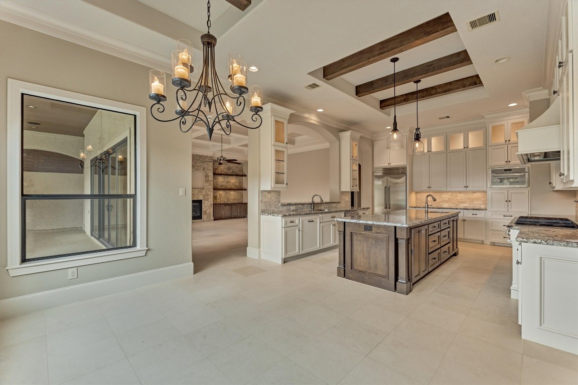 25 Post Shadow Estate Drive Spring, TX 77389 - Photo 13 of 50 Light-filled kitchen showcases beamed ceiling, oversized island, custom cabinetry, and elegant statement lighting.