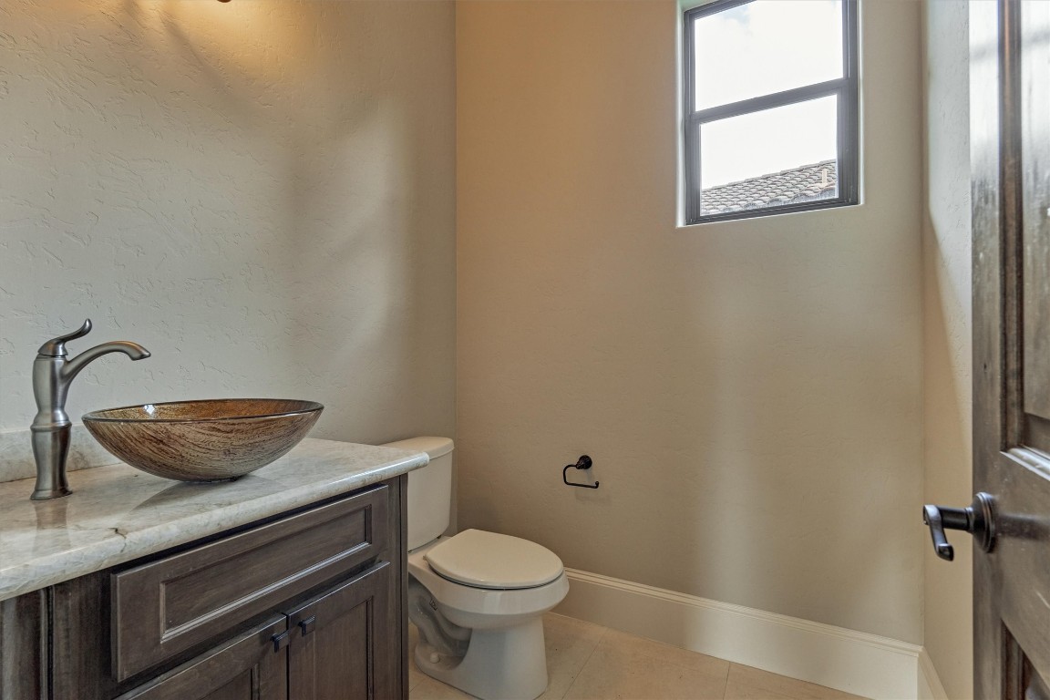 25 Post Shadow Estate Drive Spring, TX 77389 - Photo 33 of 50 Stylish powder bath with vessel sink, stone countertop, rich cabinetry, and bright window.