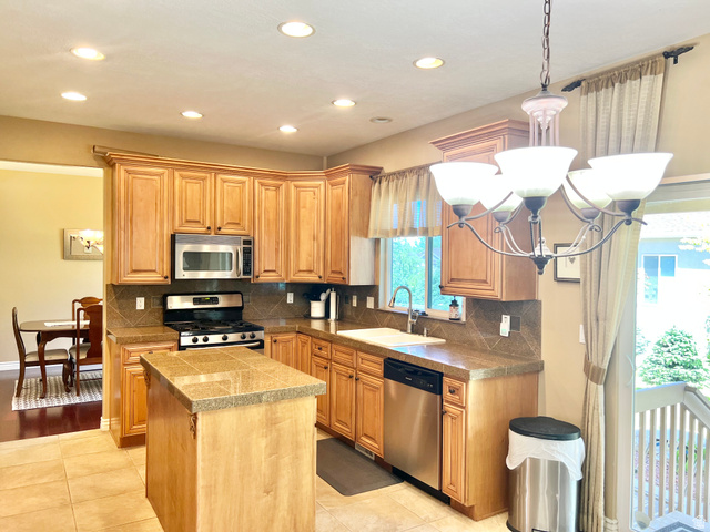 369 Culross Circle Tooele, UT 84074 - Photo 8 of 54 Kitchen featuring tile flooring, wood-finish cabinetry, tile countertops, and a tile backsplash