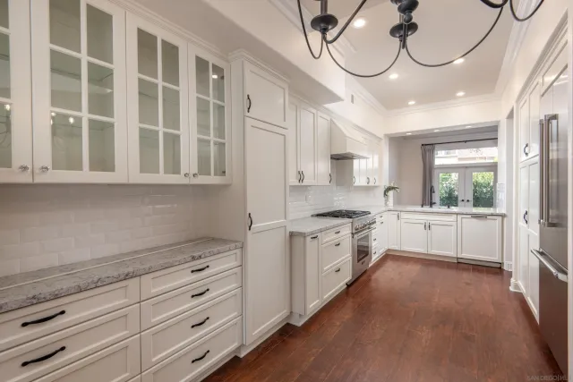 a kitchen with granite countertop a refrigerator a sink dishwasher a stove and white cabinets with wooden floor