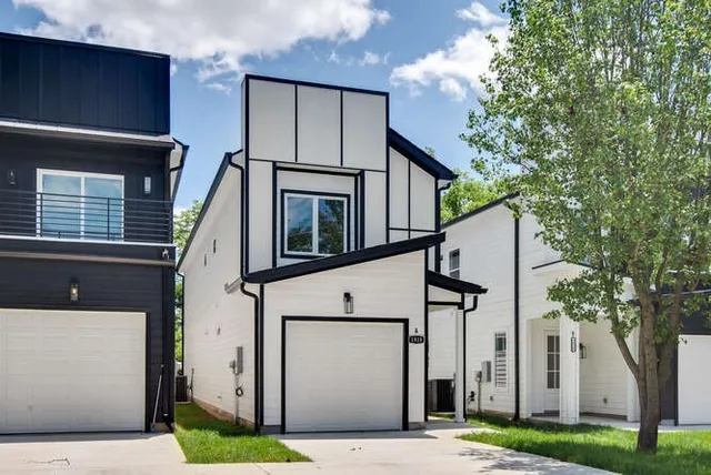 a view of a white house with large windows and a tree