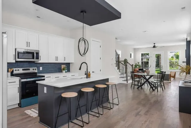 a kitchen with stainless steel appliances a table chairs in it and wooden floors