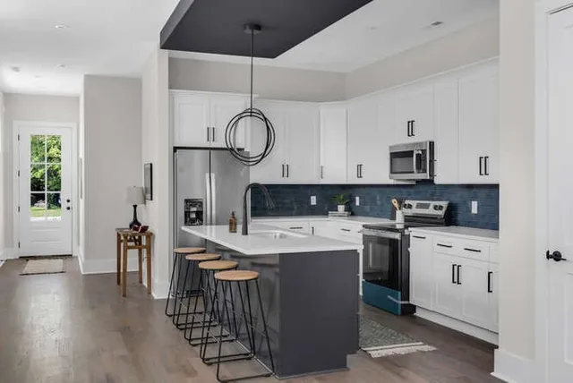 a kitchen with kitchen island granite countertop a sink a stove oven a counter space and cabinets