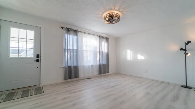 an empty room with wooden floor and windows