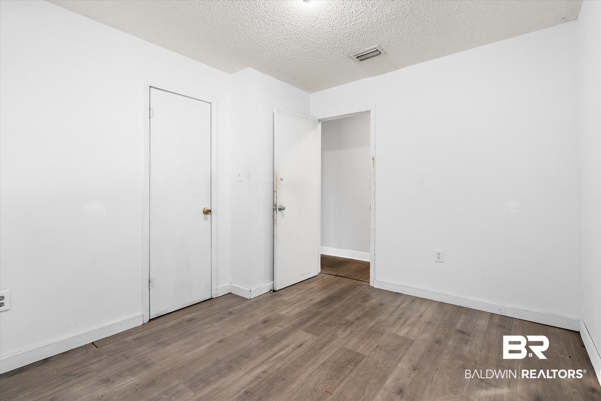 6233 Ponder Road Fairhope, AL 36532 - Photo 13 of 20 Unfurnished bedroom with hardwood / wood-style floors and a textured ceiling
