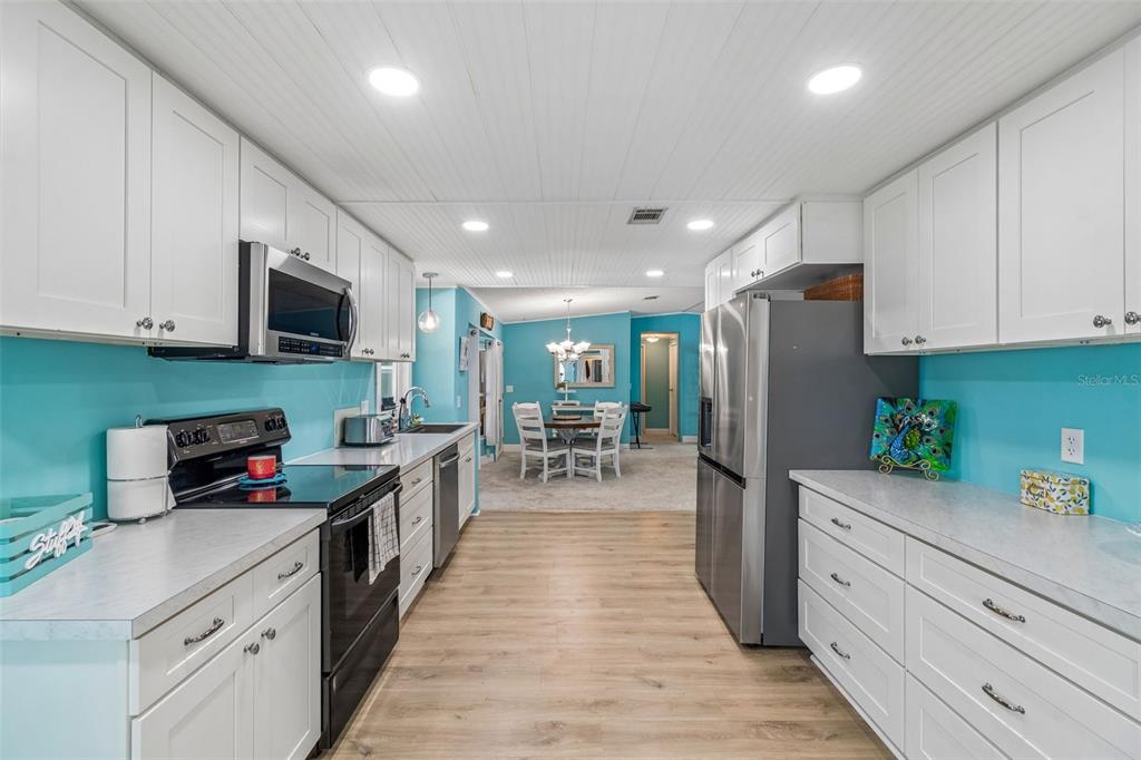 14242 Action Street Brooksville, FL 34613 - Photo 16 of 60 a kitchen with stainless steel appliances kitchen island granite countertop a refrigerator oven stove a sink dishwasher and white cabinets with wooden floor