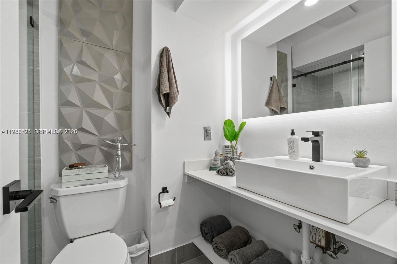 149 Northwest 70th Street, Unit 101C Boca Raton, FL 33487 - Photo 16 of 21 a bathroom with a sink mirror vanity and toilet