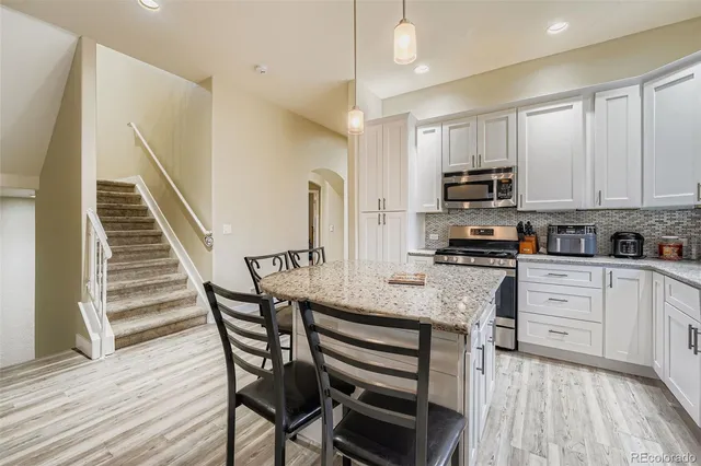 a kitchen with stainless steel appliances granite countertop a white table and chairs
