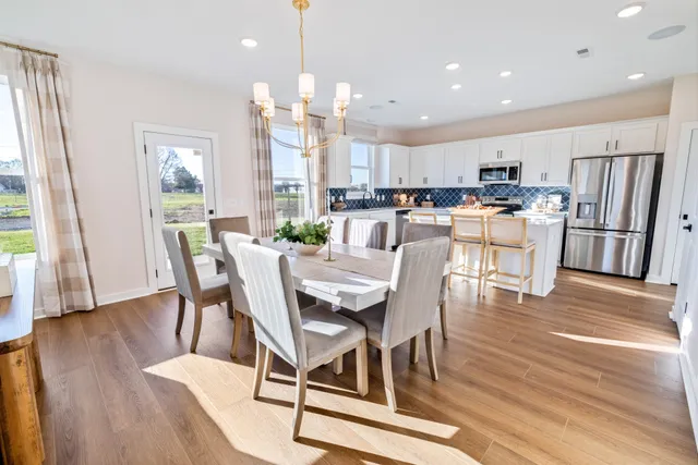 a kitchen with refrigerator a stove a sink and a dining table with wooden floor