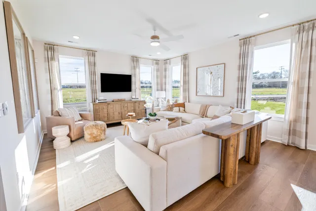 a living room with furniture a flat screen tv and a large window