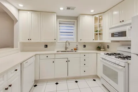 a kitchen with white cabinets white stainless steel appliances and sink