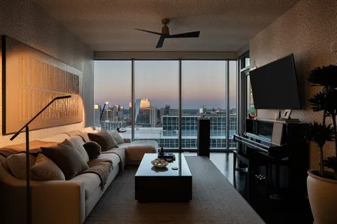 a living room with furniture a flat screen tv and a floor to ceiling window